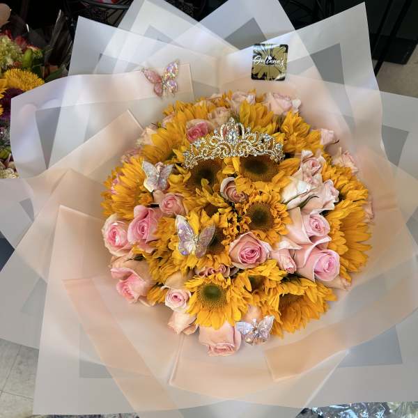 Bouquet of yellow sunflowers and pink roses with a tiara and butterfly picks