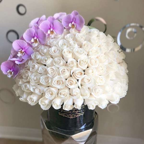 White rose bouquet with purple orchids in a metallic vase