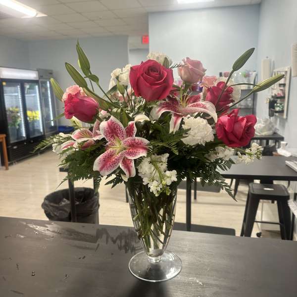Pink roses and lilies arranged in a clear glass vase
