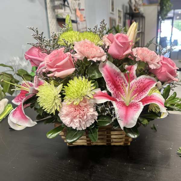 Pink roses and lilies arranged in a wicker basket