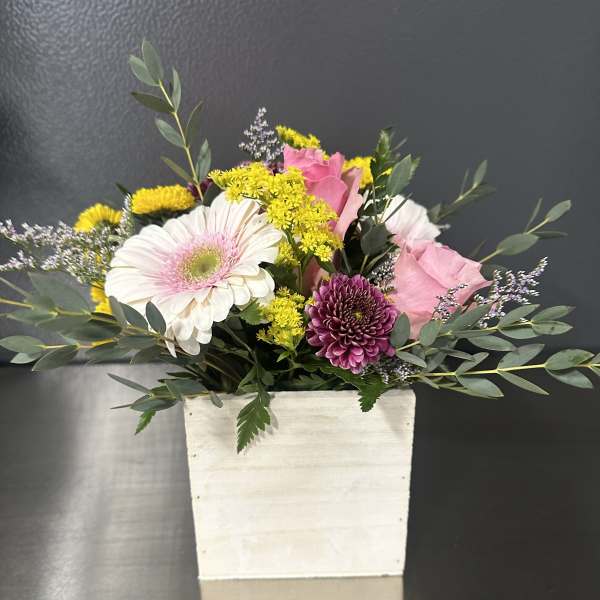 Mixed bouquet in a white rectangular vase with pink and yellow flowers