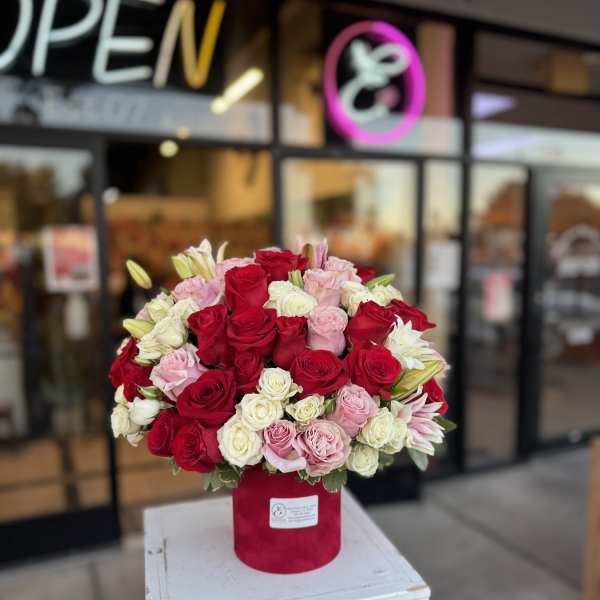 Red, pink, and white rose arrangement in a red hat box