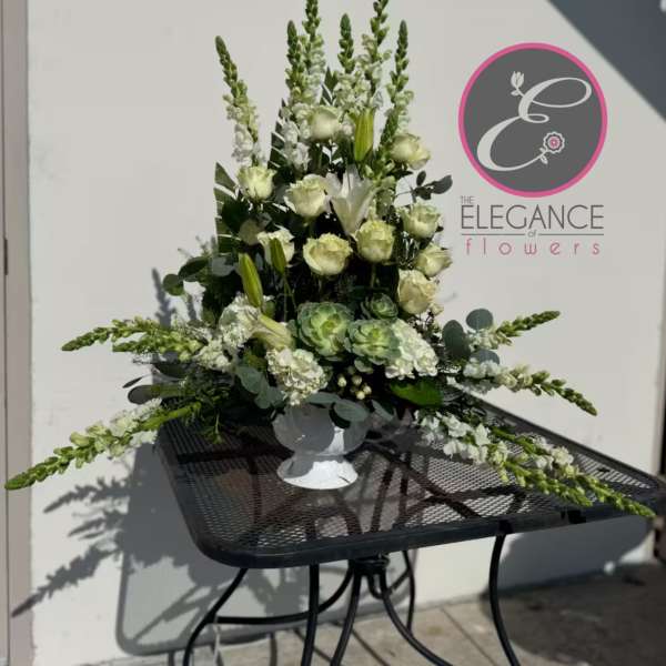 Tall white and green floral arrangement in a white pedestal vase