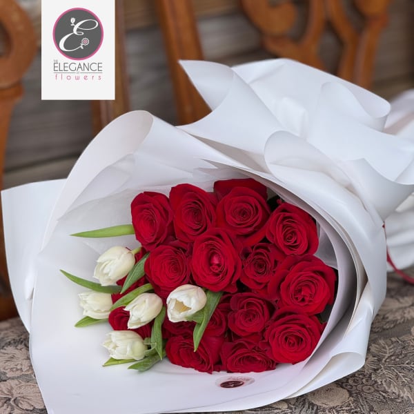 Bouquet of red roses and white tulips wrapped in white paper
