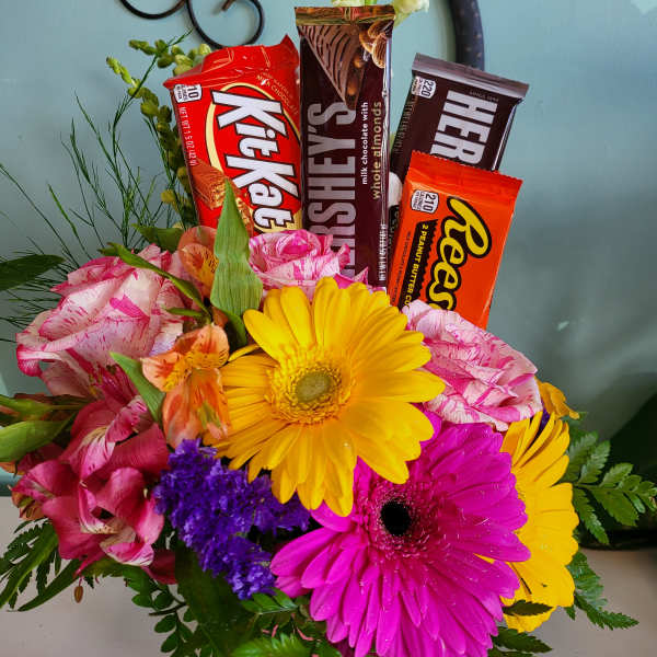 Bouquet of bright flowers with candy bars arranged in the center