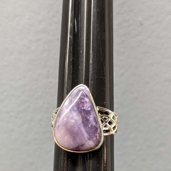 Purple teardrop gemstone ring on a dark display stand