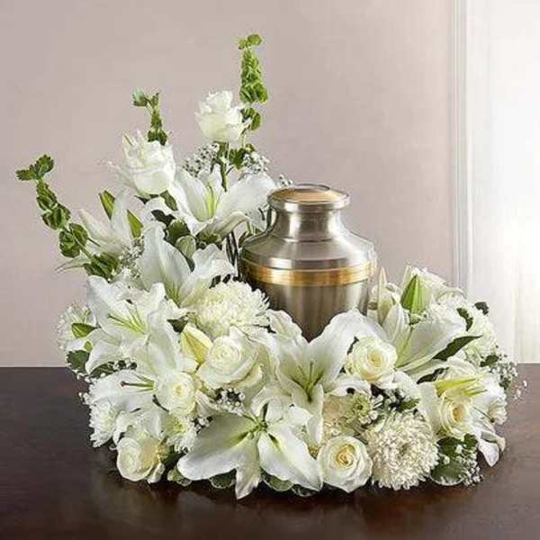 White floral funeral arrangement around a metal urn