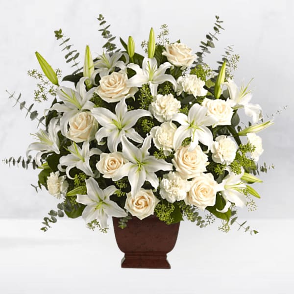 White lilies and cream roses arranged in a brown urn vase