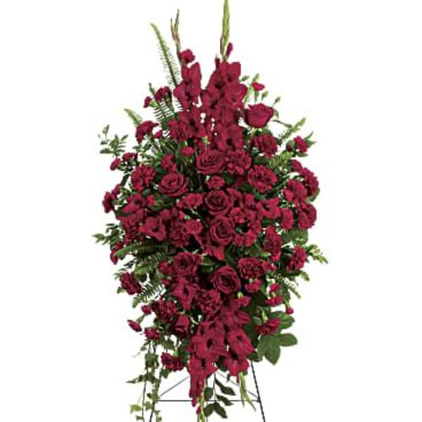 Tall standing spray of dark red roses and carnations on a metal easel