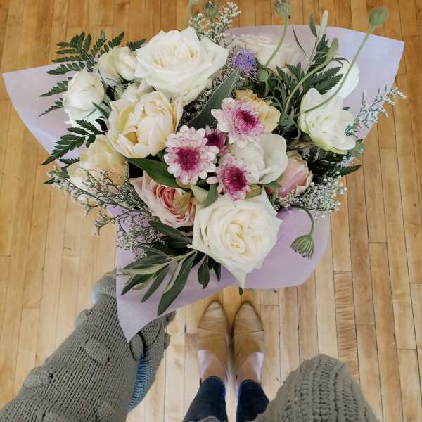 Handheld bouquet of white and blush roses with pink daisies in lavender wrap