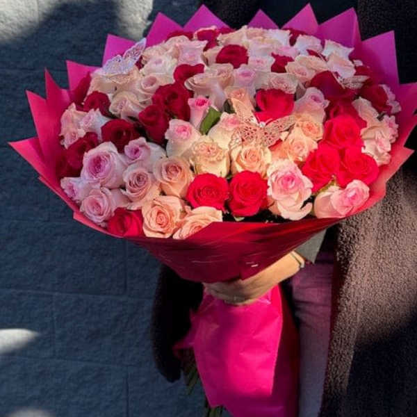 Large bouquet of pink and red roses wrapped in bright pink paper