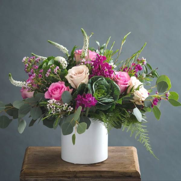 Pink and cream roses in a white vase with mixed greenery