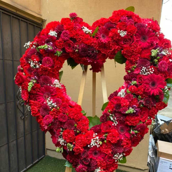 Large heart-shaped wreath of red flowers on a wooden easel