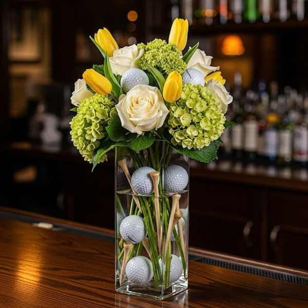 Yellow tulips and white roses in a clear vase with golf balls