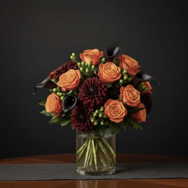 Orange roses and burgundy dahlias in a clear glass vase