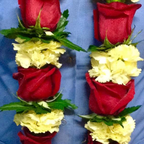 Two floral leis with red roses and pale yellow carnations