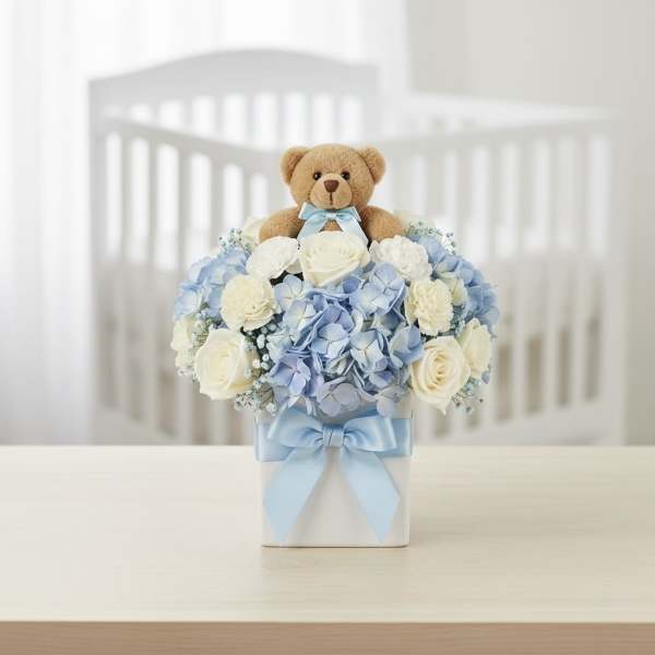 Teddy bear above a blue and white flower arrangement in a square box