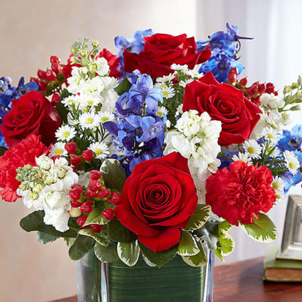 Red, white, and blue flower arrangement in a square glass vase