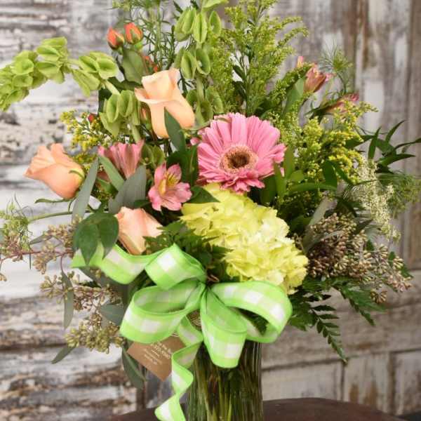 Mixed bouquet in a glass vase with pink, peach, and green blooms