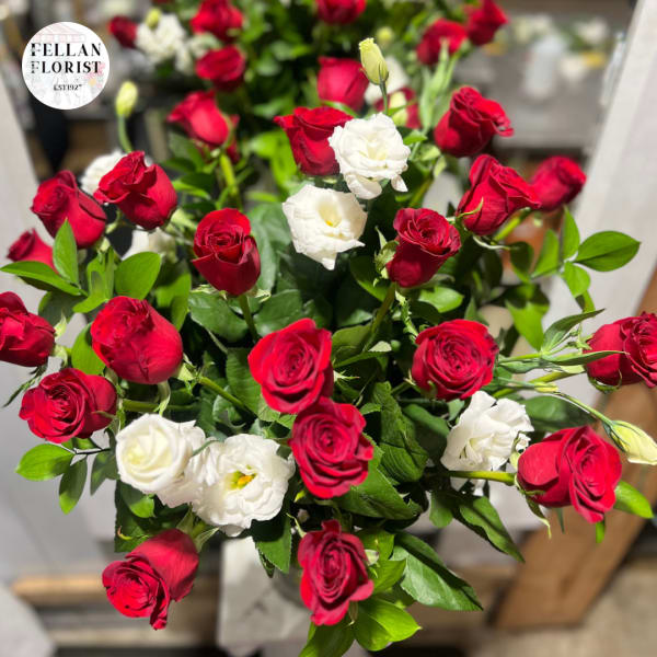 Arrangement of red roses with a few white lisianthus blooms clustered among them