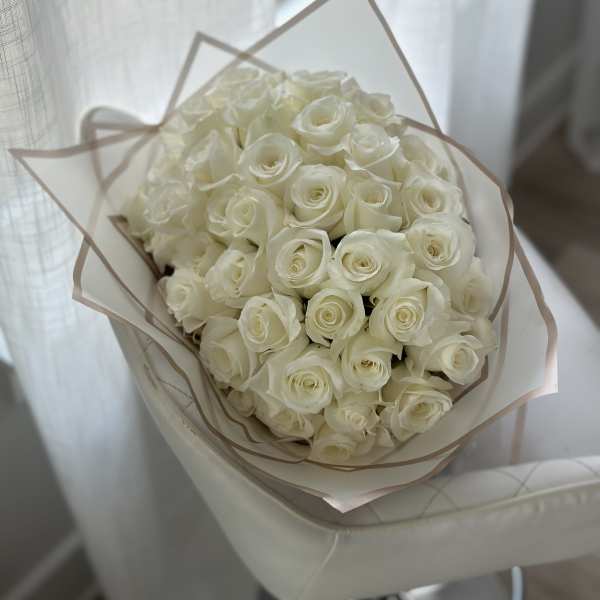 Bouquet of white roses wrapped in pale paper
