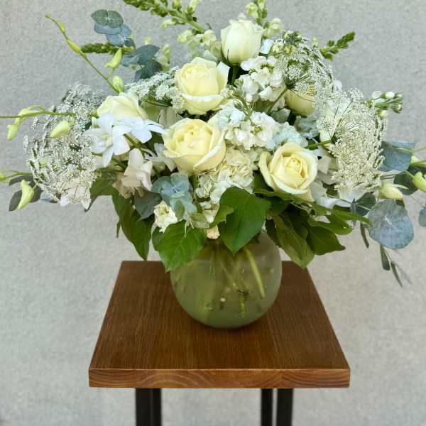 White rose bouquet in a glass vase with airy white filler flowers