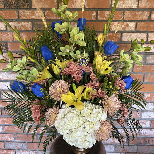 Tall mixed floral arrangement in a vase with blue, yellow, pink, and white blooms