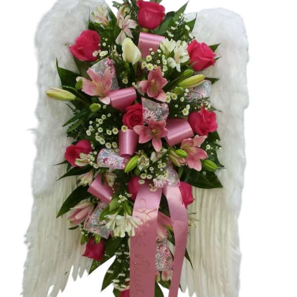 Pink and white floral arrangement with angel wings and ribbons