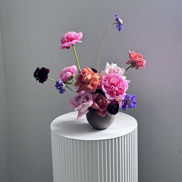 Mixed pink and purple flowers arranged in a dark vase