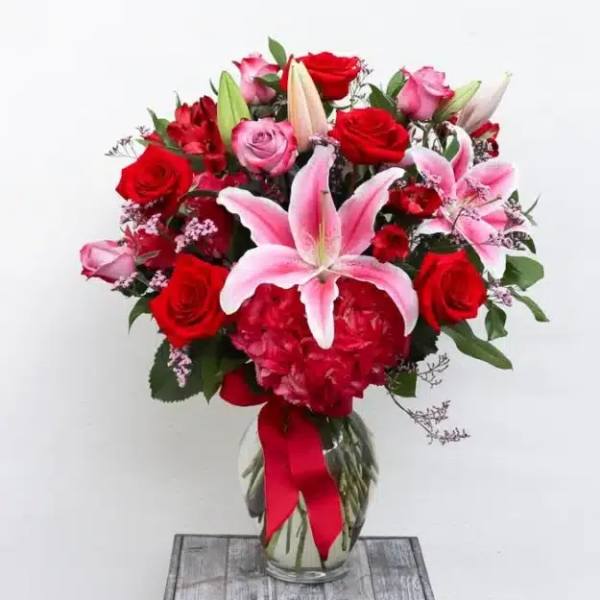 Bouquet of red and pink roses with lilies in a glass vase