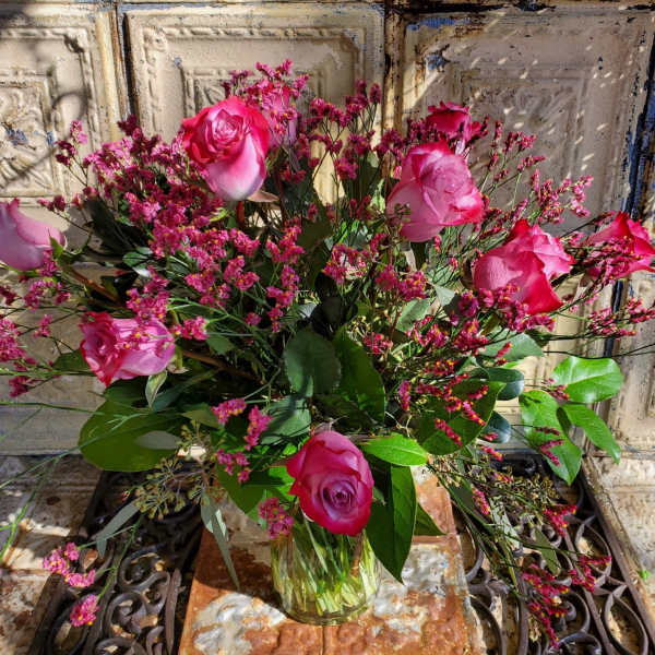 Pink roses in a clear glass vase with small pink filler flowers