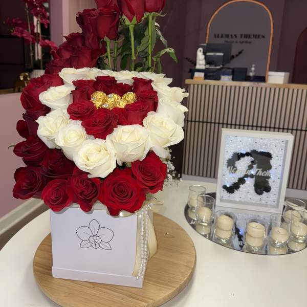 Red and white roses arranged in a square box with gold chocolates