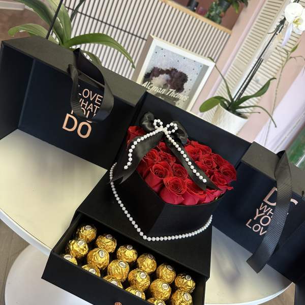 Black gift boxes with red roses and gold-wrapped chocolates