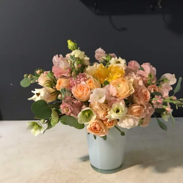 Pastel bouquet of peach, pink, and white flowers in a pale vase