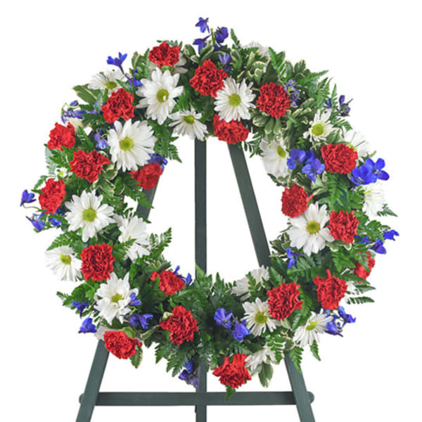 Circular wreath of red, white, and blue flowers on a standing easel
