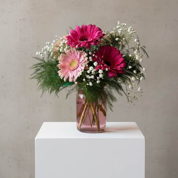 Pink gerbera daisies in a glass vase with baby's breath