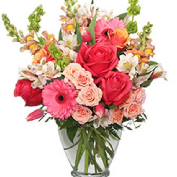 Mixed bouquet of pink and red flowers in a clear glass vase
