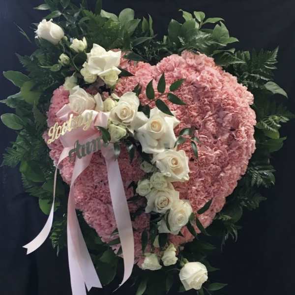 Pink heart-shaped floral wreath with white roses and ribbon
