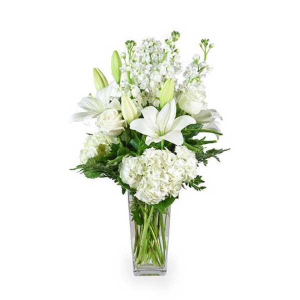 White lilies and hydrangeas in a clear glass vase