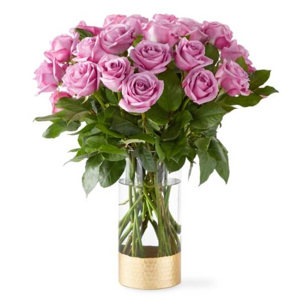 Pink roses arranged in a clear glass vase with a gold base