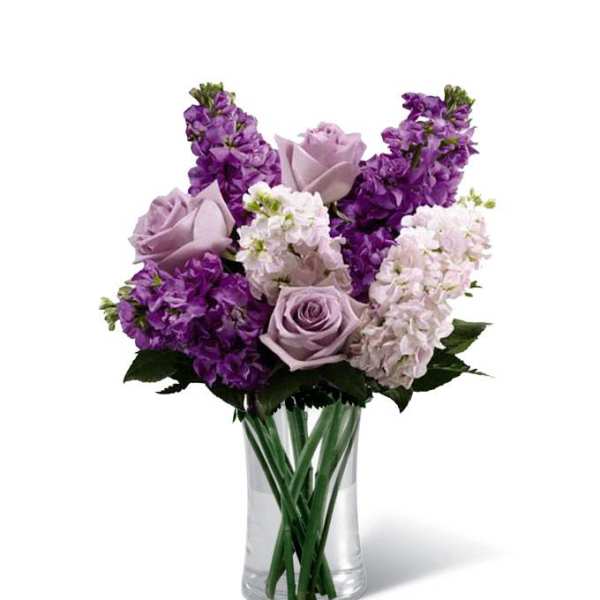 Purple and lavender flowers arranged in a clear glass vase