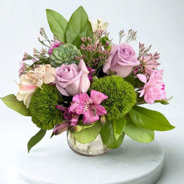 Pink and lavender bouquet in a clear glass vase with green accents