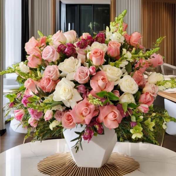 Large pink and white rose arrangement in a white vase