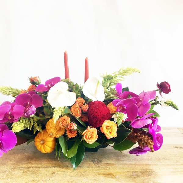 Low floral centerpiece with orchids, roses, and candles