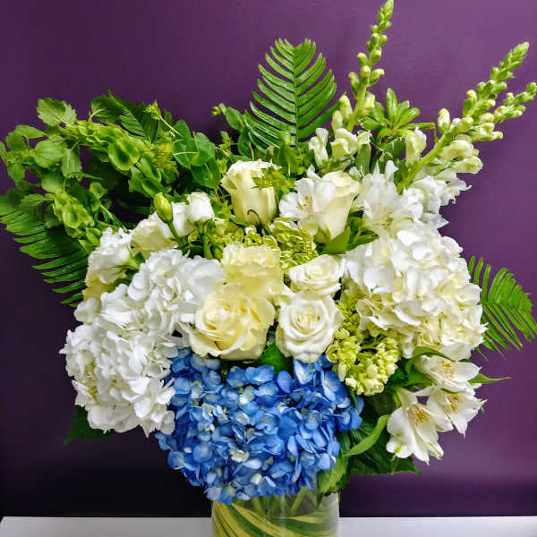 White and blue floral arrangement in a glass vase
