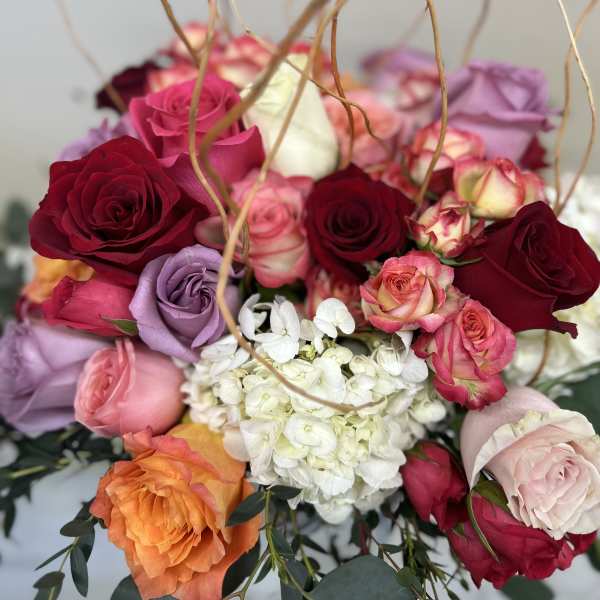 Bouquet of multicolored roses with white hydrangea and curly branches