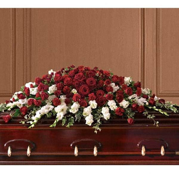 Red and white floral casket spray on a wooden casket