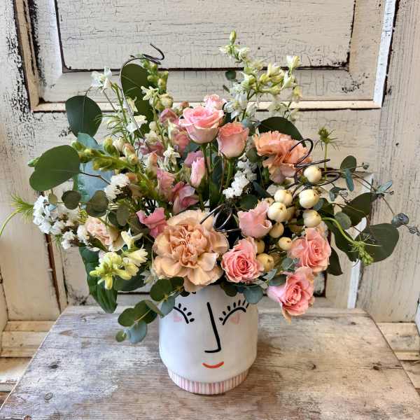 Pink and peach bouquet in a white face vase