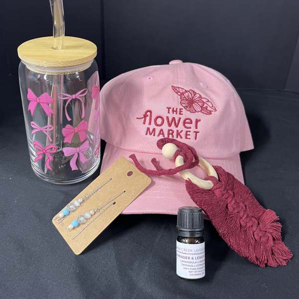 Pink flower market cap with a clear tumbler, earrings, tassel keychain, and small bottle