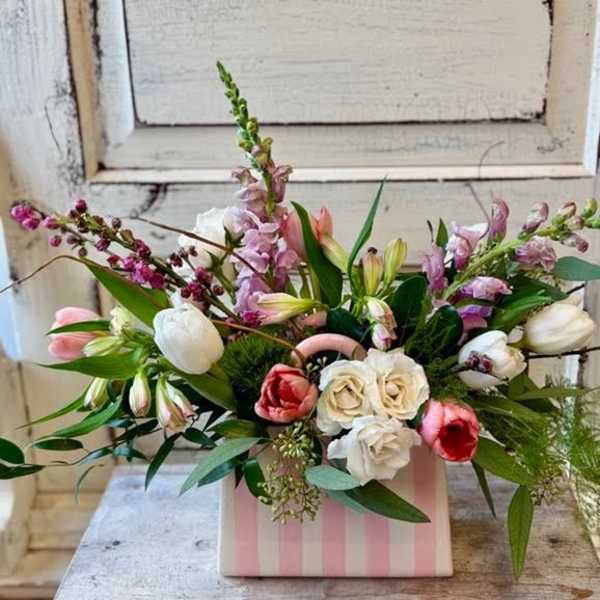 Mixed bouquet of tulips, roses, and snapdragons in a pink striped box